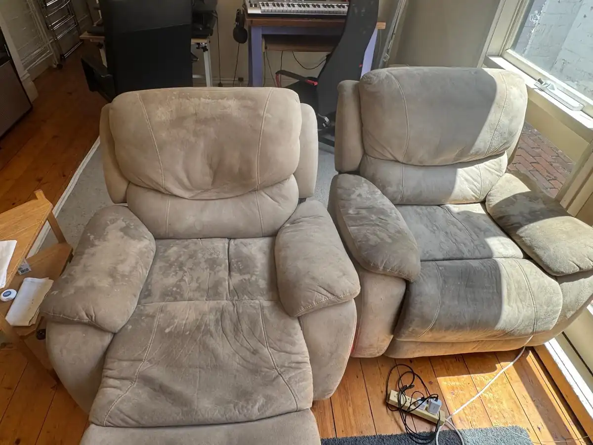 Two suede recliner armchairs with one cleaned and one still soiled, showing the difference