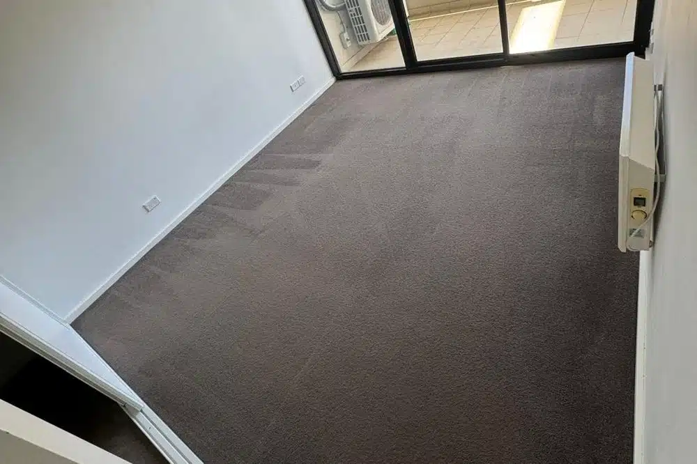 Empty bedroom with freshly cleaned carpet beside the balcony door